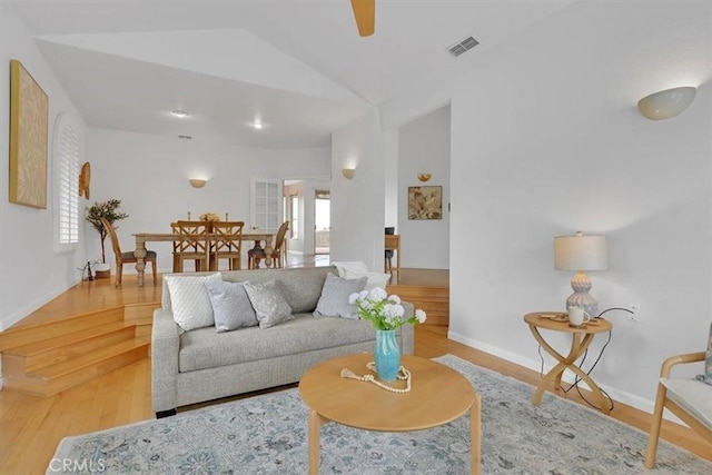 living area featuring visible vents, baseboards, wood finished floors, and vaulted ceiling