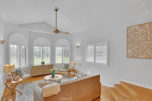 sitting room with ceiling fan, vaulted ceiling, baseboards, and wood finished floors