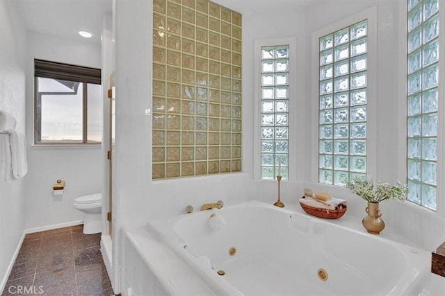 full bathroom with baseboards, a whirlpool tub, and toilet