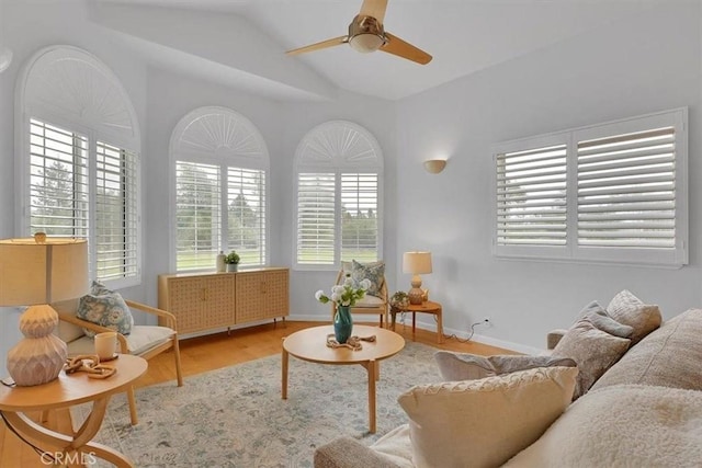 living room with baseboards, ceiling fan, vaulted ceiling, and wood finished floors