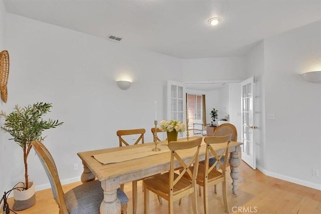 dining area with light wood-style floors, baseboards, french doors, and visible vents