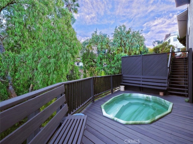view of swimming pool with hot tub deck surround and a deck