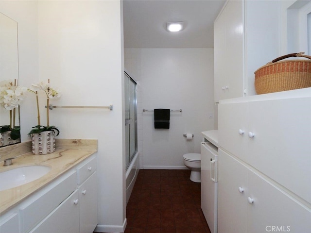 bathroom with combined bath / shower with glass door, baseboards, toilet, tile patterned floors, and vanity