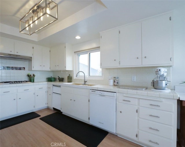 kitchen with light wood finished floors, a sink, under cabinet range hood, tasteful backsplash, and dishwasher