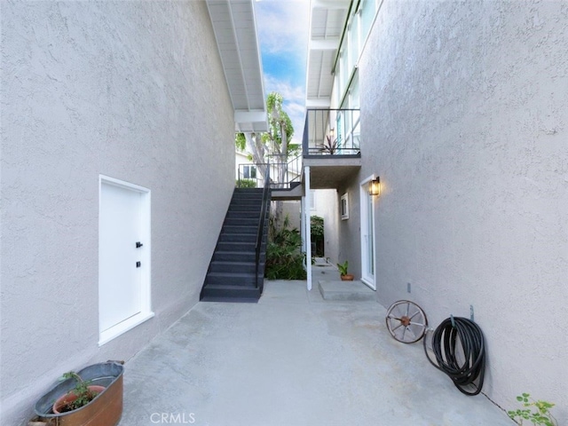 view of side of property with stairway, stucco siding, and a patio area