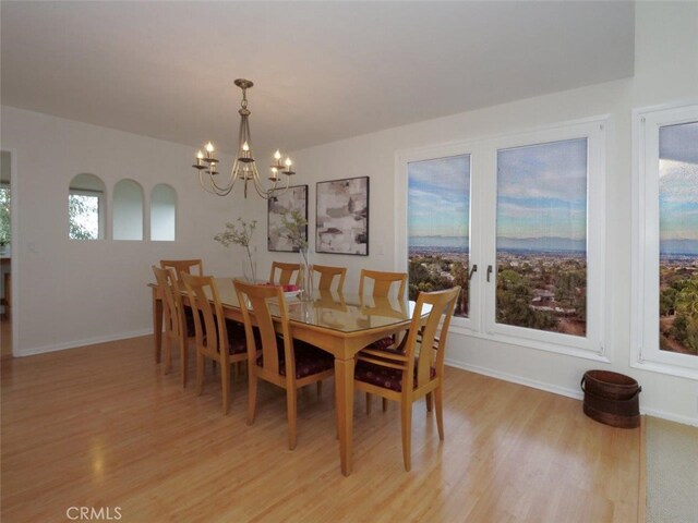 dining space with baseboards, a notable chandelier, and light wood finished floors