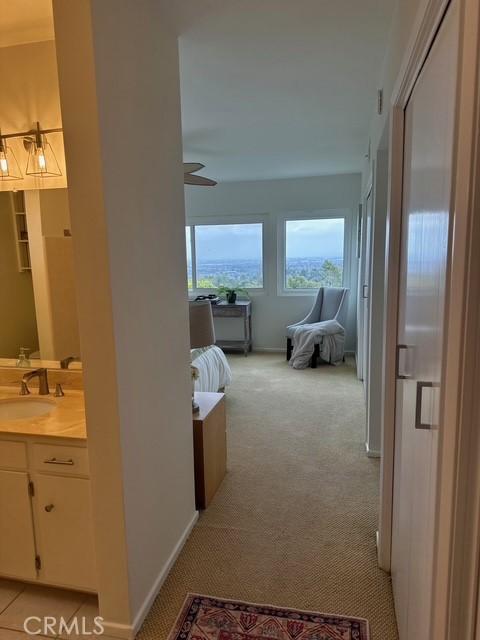 corridor featuring light carpet, baseboards, and a sink
