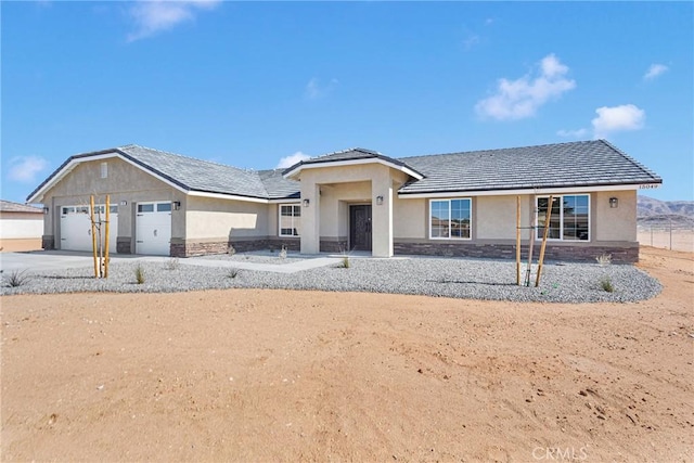 view of front facade featuring a garage, stone siding, driveway, and stucco siding