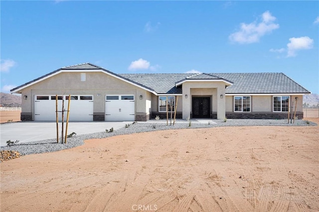 single story home featuring a garage, stone siding, driveway, and stucco siding