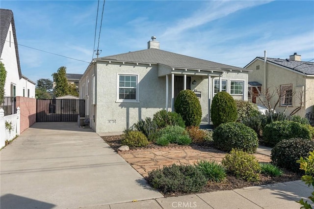 bungalow-style house featuring a gate, fence, a chimney, and stucco siding