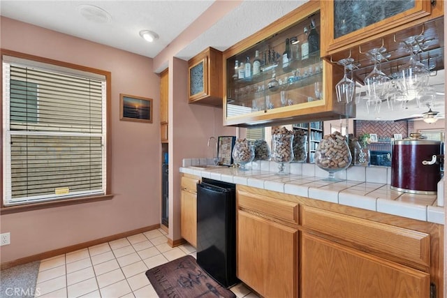 bar with light tile patterned flooring, a sink, wet bar, baseboards, and fridge