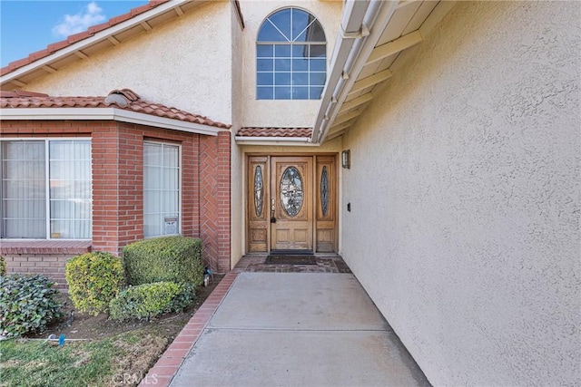 doorway to property featuring a tiled roof and stucco siding