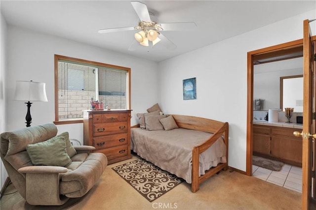 bedroom with light carpet, light tile patterned floors, ensuite bath, and a ceiling fan