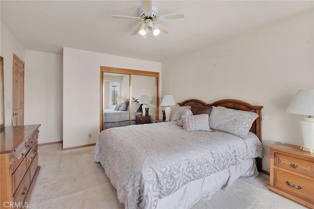 bedroom with a ceiling fan, a closet, light colored carpet, and baseboards