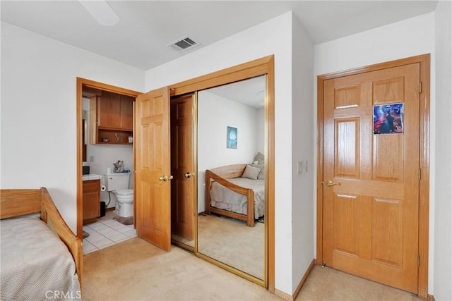 bedroom with a closet, visible vents, light carpet, connected bathroom, and baseboards