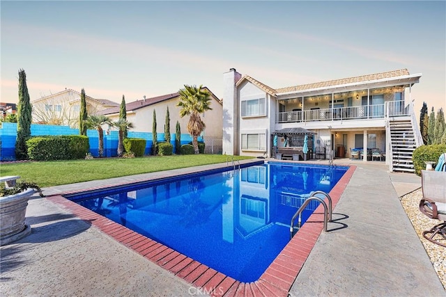 pool at dusk with a fenced in pool, a lawn, stairway, fence, and a patio area