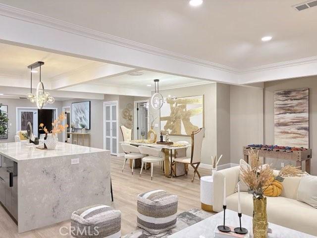 living room with a chandelier, visible vents, ornamental molding, and light wood-style flooring