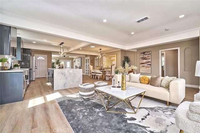 living room featuring crown molding, recessed lighting, visible vents, and light wood-style floors