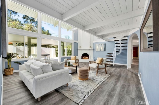 sunroom with arched walkways, wood ceiling, a brick fireplace, and beam ceiling