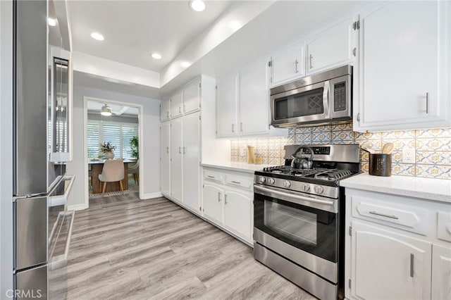 kitchen with stainless steel appliances, light countertops, decorative backsplash, white cabinetry, and light wood-type flooring