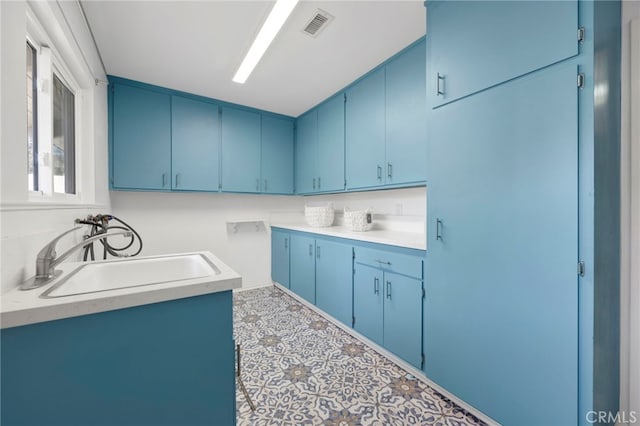 kitchen featuring light countertops, blue cabinetry, and a sink