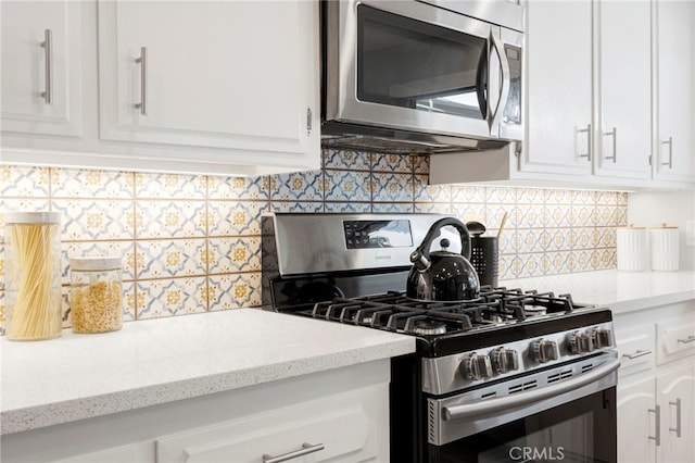 kitchen with appliances with stainless steel finishes, backsplash, white cabinetry, and light stone countertops