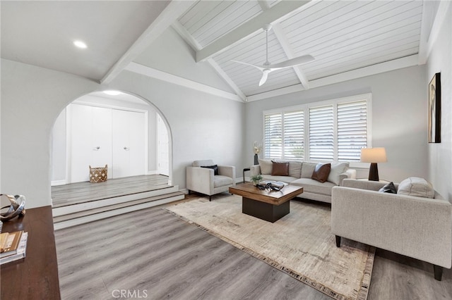 living room featuring arched walkways, wood finished floors, a ceiling fan, and vaulted ceiling with beams