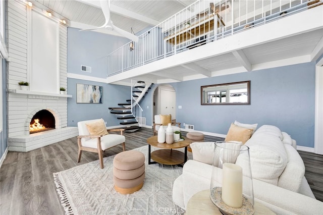 living room with baseboards, stairway, wood finished floors, a high ceiling, and a fireplace