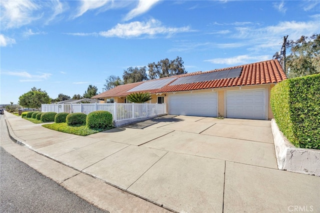 ranch-style home featuring an attached garage, a tiled roof, concrete driveway, roof mounted solar panels, and stucco siding