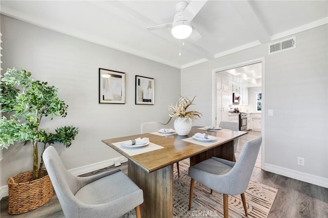 dining space featuring baseboards, visible vents, ceiling fan, dark wood-style flooring, and beamed ceiling