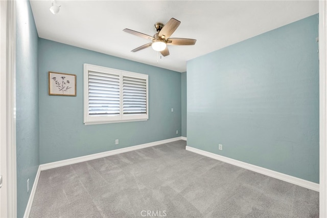 spare room featuring light colored carpet, ceiling fan, and baseboards