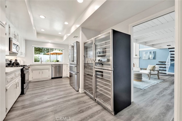 kitchen with white cabinets, light wood-style flooring, stainless steel appliances, and light countertops