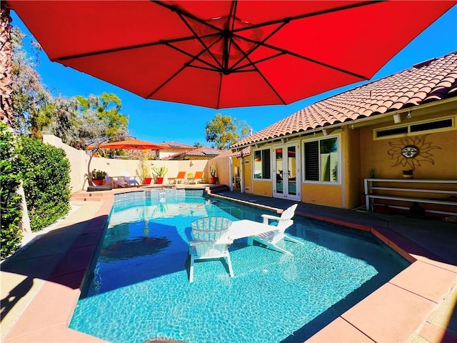 view of swimming pool with a patio area, french doors, a fenced in pool, and a fenced backyard