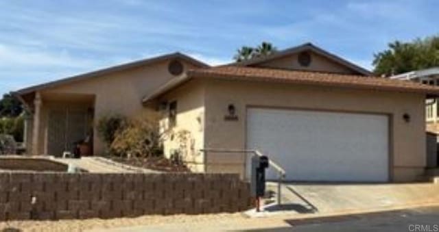 view of front of property with a garage, concrete driveway, and stucco siding