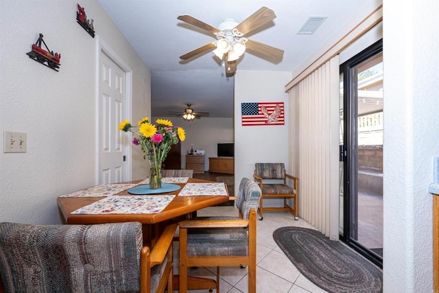 dining area featuring visible vents, ceiling fan, light tile patterned flooring, and a textured wall