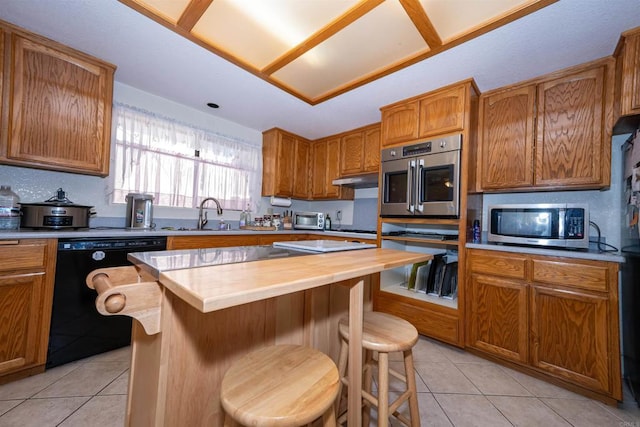 kitchen featuring light tile patterned floors, a sink, a kitchen breakfast bar, stainless steel appliances, and butcher block countertops
