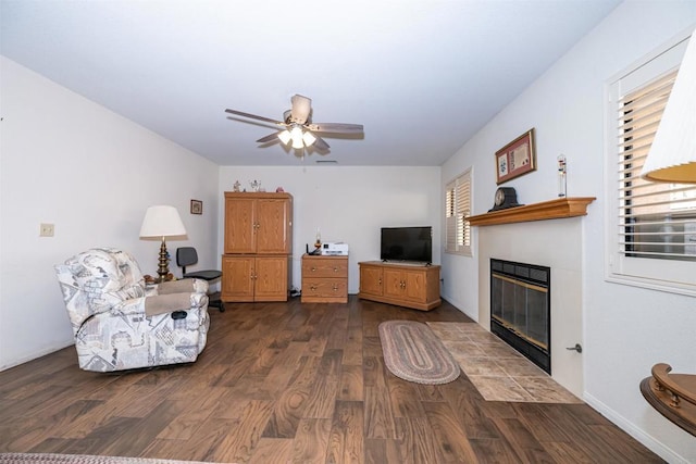 living room featuring a fireplace with flush hearth, a ceiling fan, and wood finished floors