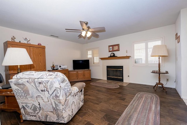 living area featuring a fireplace with flush hearth, dark wood-style floors, visible vents, and a ceiling fan