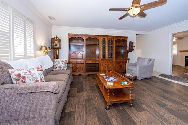 living area with crown molding, visible vents, a ceiling fan, and wood finished floors