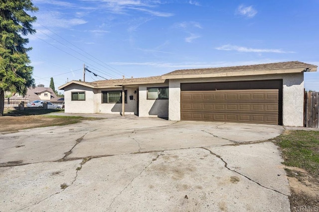 view of front of property with an attached garage, driveway, fence, and stucco siding