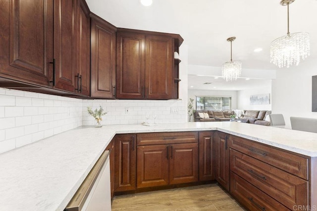 kitchen featuring tasteful backsplash, open floor plan, hanging light fixtures, light wood-type flooring, and a notable chandelier