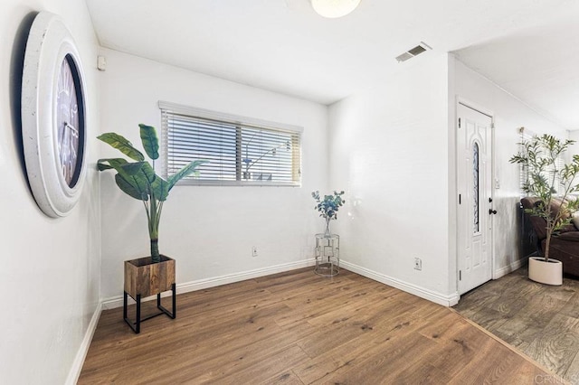 interior space with dark wood finished floors, visible vents, and baseboards