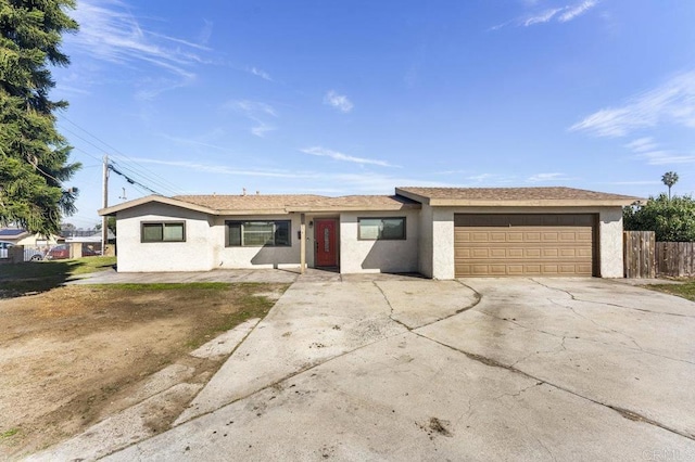 ranch-style home with concrete driveway, an attached garage, fence, and stucco siding