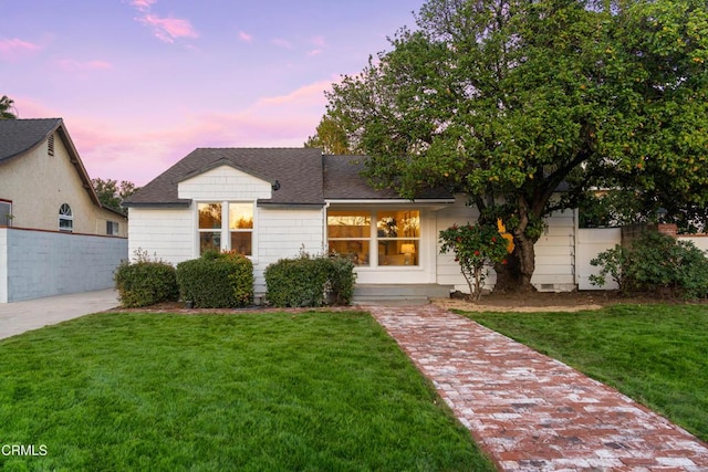 view of front of house with a yard, a shingled roof, and fence