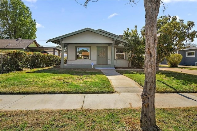 bungalow-style house with stucco siding and a front yard