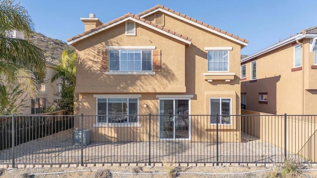 view of front of house with a patio, fence, a tiled roof, stucco siding, and a chimney