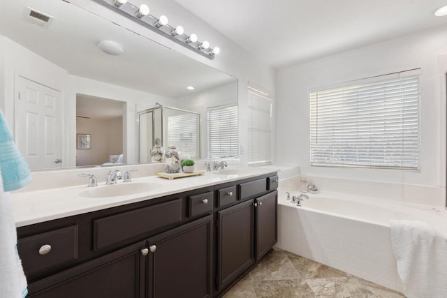 bathroom featuring a sink, visible vents, a shower stall, a bath, and double vanity