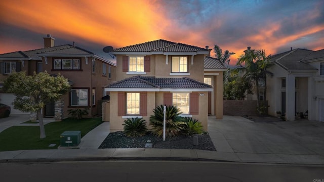 view of front of property with a tiled roof, a front lawn, concrete driveway, and stucco siding