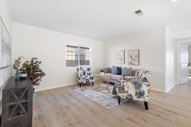 living room featuring light wood-style floors, baseboards, and visible vents