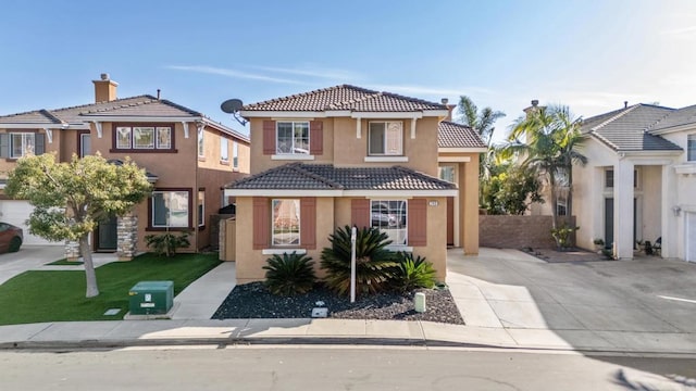 view of front of property with a tile roof, driveway, a front lawn, and stucco siding